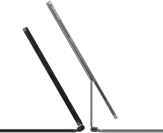 Dva iPady Pro připnuté k Magic Keyboardu, pohled z boku, tenký profil, vesmírně černá barva, reproduktory a USB‑C port, jeden napůl otevřený, druhý ve stříbrné barvě otevřený a nakloněný dozadu, takže je vidět plovoucí konzolová konstrukce klávesnice, reproduktory a mikrofon